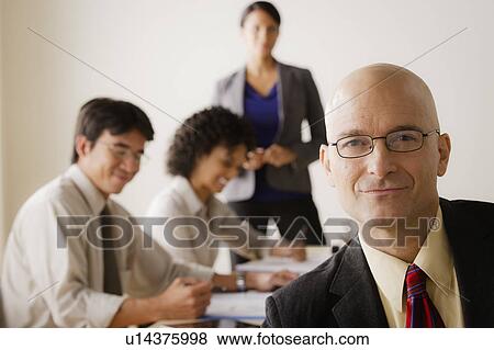 Mature businessman looking at camera, business team in background View Large Photo Image Stock Photo - Mature businessman looking at camera, business team in background. Fotosearch