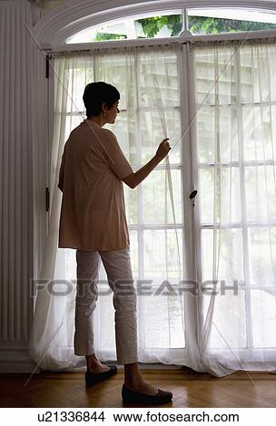 Mature woman looking through window View Large Photo Image Picture - Mature woman looking through window. Fotosearch