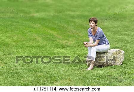 Mature woman sitting on rock View Large Photo Image Picture - Mature woman sitting on rock. Fotosearch