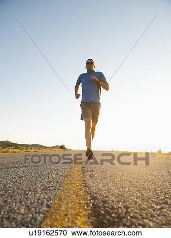 Mid adult couple running on empty road View Large Photo Image Stock Image - Mid adult couple running on empty road. Fotosearch