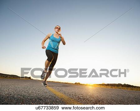 Mid adult couple running on empty road View Large Photo Image Stock Photo - Mid adult couple running on empty road. Fotosearch