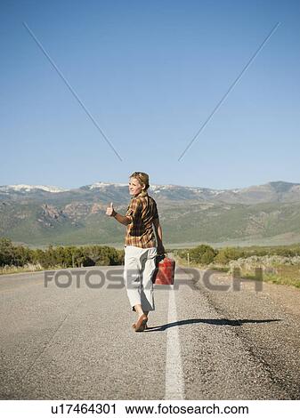 Mid adult woman carrying empty canister attempting to stop vehicles for help View Large Photo Image Stock Image - Mid adult woman carrying empty canister attempting to stop vehicles for help. Fotosearch