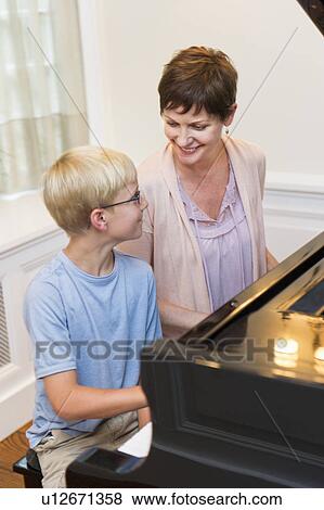Stock Photo - Mother and son (10-11) playing grand piano. Fotosearch