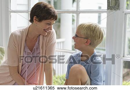 Stock Photography - Mother and son (10-11) sitting in front of window. Fotosearch