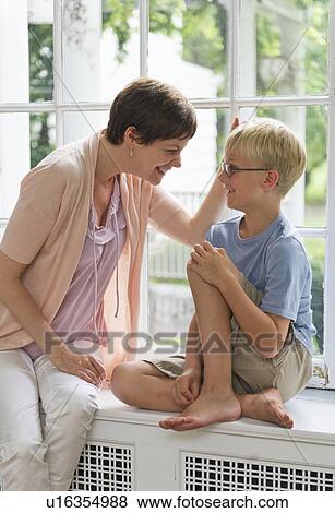Stock Photo - Mother and son (10-11) sitting on window seat. Fotosearch