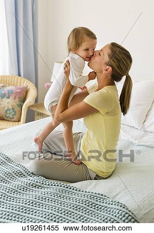 Mother kissing daughter (2-3) on bed View Large Photo Image Stock Photography - Mother kissing daughter (2-3) on bed. Fotosearch