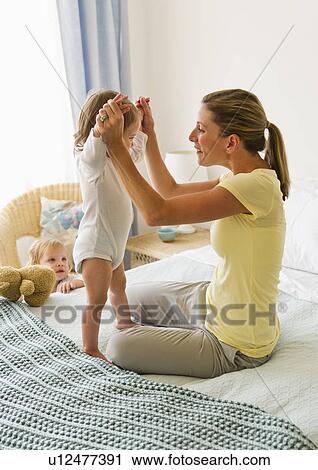 Mother playing with daughter (2-3) on bed View Large Photo Image Stock Image - Mother playing with daughter (2-3) on bed. Fotosearch