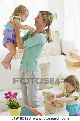 Stock Image - Mother playing with daughters (2-3) in living room. Fotosearch