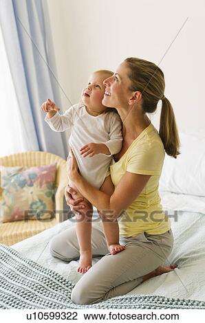 Stock Image - Mother with daughter (2-3) on bed. Fotosearch