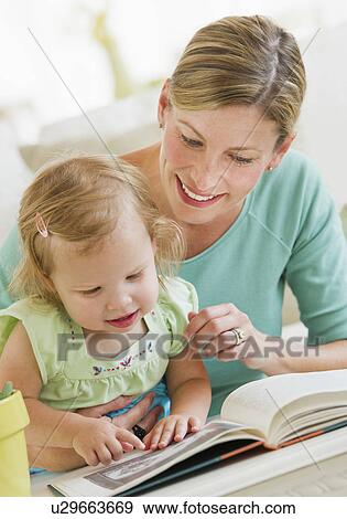 Mother with daughter (2-3) reading book in living room View Large Photo Image Stock Photo - Mother with daughter (2-3) reading book in living room. Fotosearch