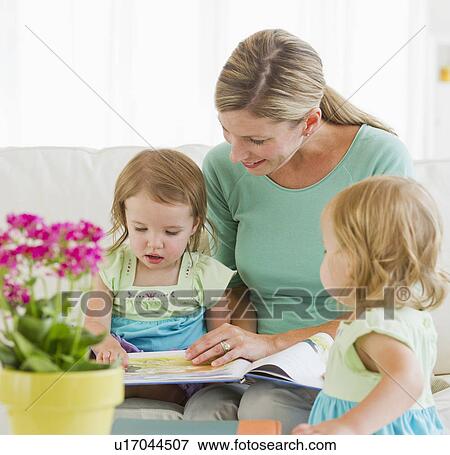 Mother with daughters (2-3) reading book on sofa View Large Photo Image Stock Photo - Mother with daughters (2-3) reading book on sofa. Fotosearch