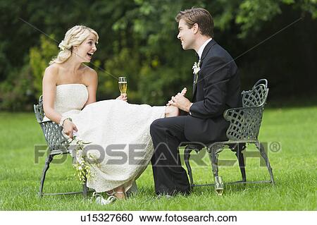 Stock Image - Newly wed couple sitting, groom massaging bride's feet. Fotosearch
