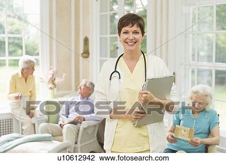 Stock Image - Nurse and senior people in nursing home. Fotosearch