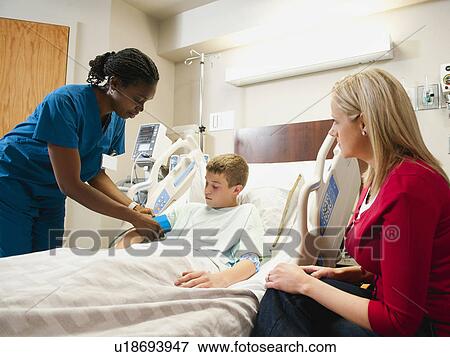 Nurse checking blood pressure to boy (10-11), mother is sitting next to bed View Large Photo Image Stock Photo - Nurse checking blood pressure to boy (10-11), mother is sitting next to bed. Fotosearch