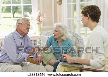 Stock Photograph - Nursing assistant talking with seniors in Nursing home. Fotosearch