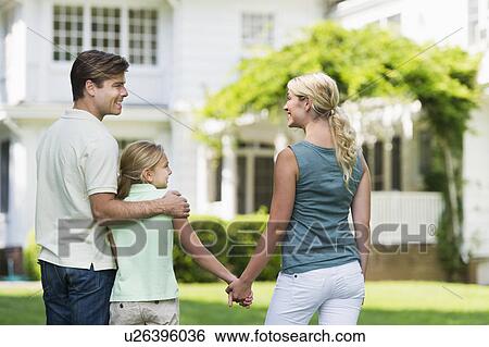 Stock Photograph - Parents with daughter (10-11) in front of house. Fotosearch