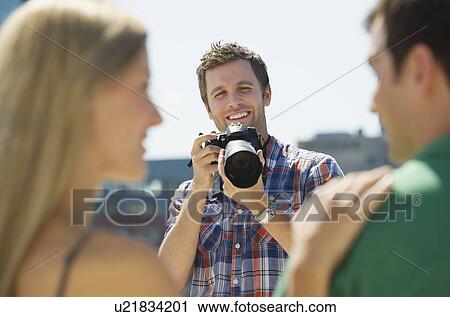 Stock Image - Photographer taking picture of couple. Fotosearch