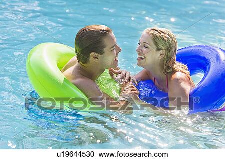 Stock Image - Portrait couple in swimming pool. Fotosearch