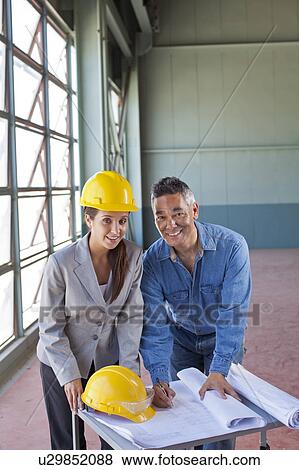 Stock Photo - Portrait of architects drawing blueprint. Fotosearch