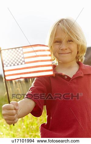 Portrait of boy (6-7) waving American flag in meadow View Large Photo Image Picture - Portrait of boy (6-7) waving American flag in meadow. Fotosearch