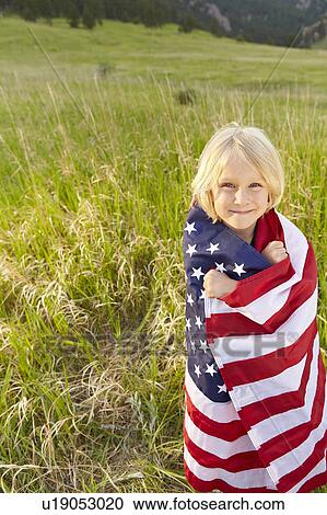 Stock Image - Portrait of boy (6-7) wrapped in American flag. Fotosearch