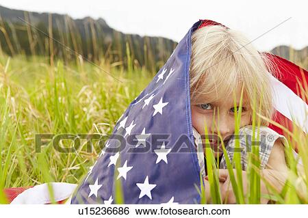 Stock Photograph - Portrait of boy (6-7) wrapped in American flag. Fotosearch