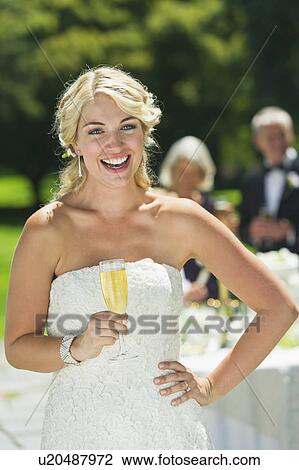 Stock Image - Portrait of bride holding champagne flute. Fotosearch