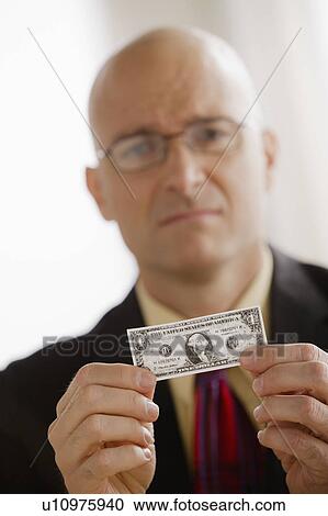 Stock Image - Portrait of business man holding one dollar bill. Fotosearch