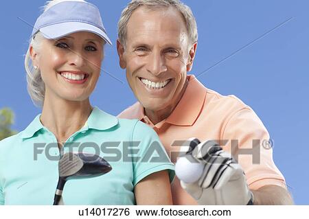 Stock Photograph - Portrait of couple holding golf club and ball. Fotosearch