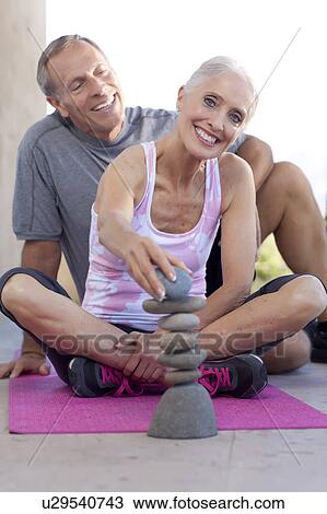 Stock Image - Portrait of couple stacking pebbles. Fotosearch