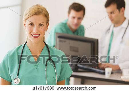 Stock Photograph - Portrait of female doctor in front of nurse's station. Fotosearch