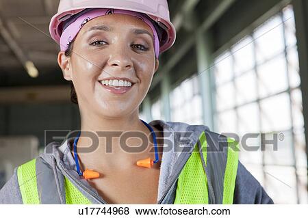 Stock Photo - Portrait of female manual worker wearing hardhat. Fotosearch