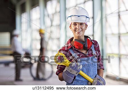 Stock Photography - Portrait of female manual worker wearing hardhat. Fotosearch