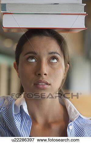 Portrait of female student balancing stack of books on head View Large Photo Image Stock Photo - Portrait of female student balancing stack of books on head. Fotosearch