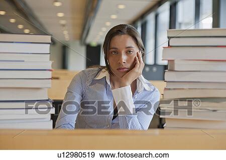 Portrait of female student between stacks of books View Large Photo Image Stock Photo - Portrait of female student between stacks of books. Fotosearch