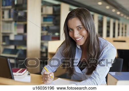 Stock Photograph - Portrait of female student studying in library. Fotosearch