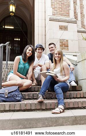 Stock Image - Portrait of four college students sitting on steps. Fotosearch