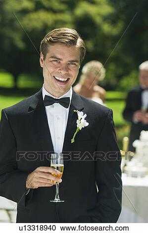 Stock Image - Portrait of groom holding champagne flute. Fotosearch