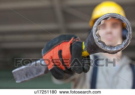 Stock Image - Portrait of male manual worker holding tool. Fotosearch
