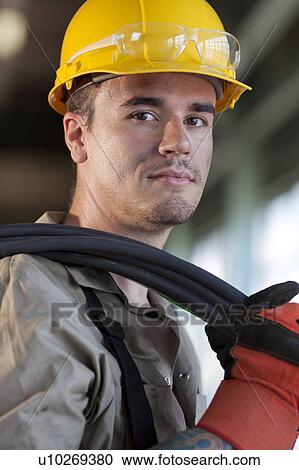 Stock Image - Portrait of male manual worker wearing hardhat. Fotosearch