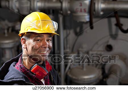 Stock Image - Portrait of male manual worker wearing hardhat. Fotosearch