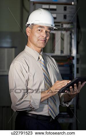 Stock Image - Portrait of male technician wearing hardhat. Fotosearch