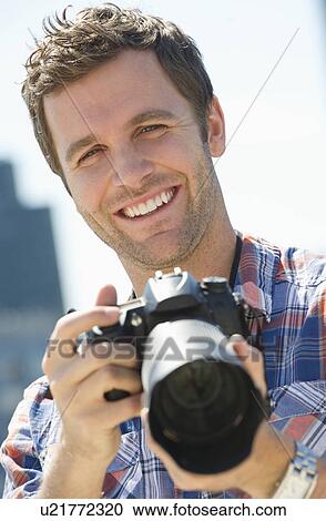 Stock Image - Portrait of man holding camera. Fotosearch