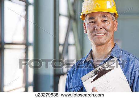 Portrait of man wearing hardhat holding clipboard View Large Photo Image Stock Photo - Portrait of man wearing hardhat holding clipboard. Fotosearch