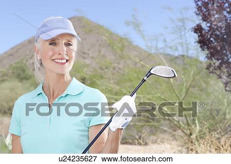 Portrait of mature woman holding golf club View Large Photo Image Stock Photo - Portrait of mature woman holding golf club. Fotosearch