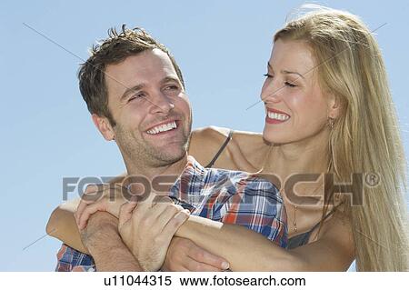 Stock Photography - Portrait of mid adult couple against blue sky. Fotosearch