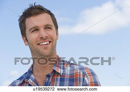 Portrait of mid adult man against blue sky View Large Photo Image Stock Image - Portrait of mid adult man against blue sky. Fotosearch