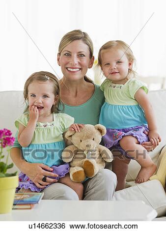 Stock Photograph - Portrait of mother with daughters (2-3) on sofa. Fotosearch