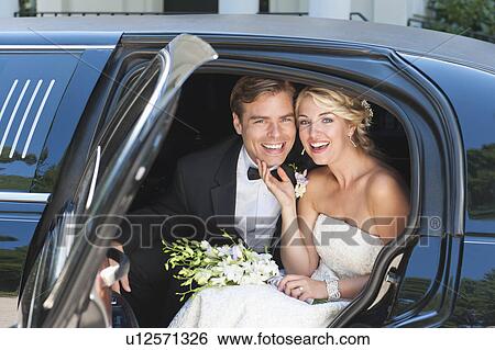 Stock Photograph - Portrait of newly wed couple sitting in limousine. Fotosearch