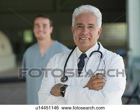 Stock Photograph - Portrait of senior doctor with orderly in background. Fotosearch